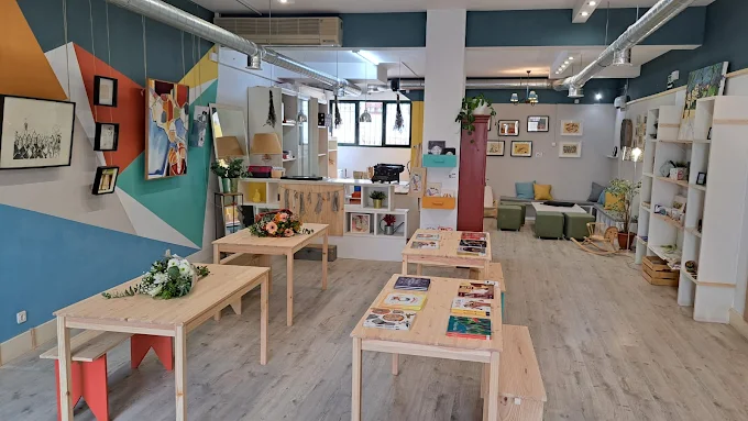 Interior luminoso de Borrajeto con mesas de madera, libros y cuadros en paredes de colores